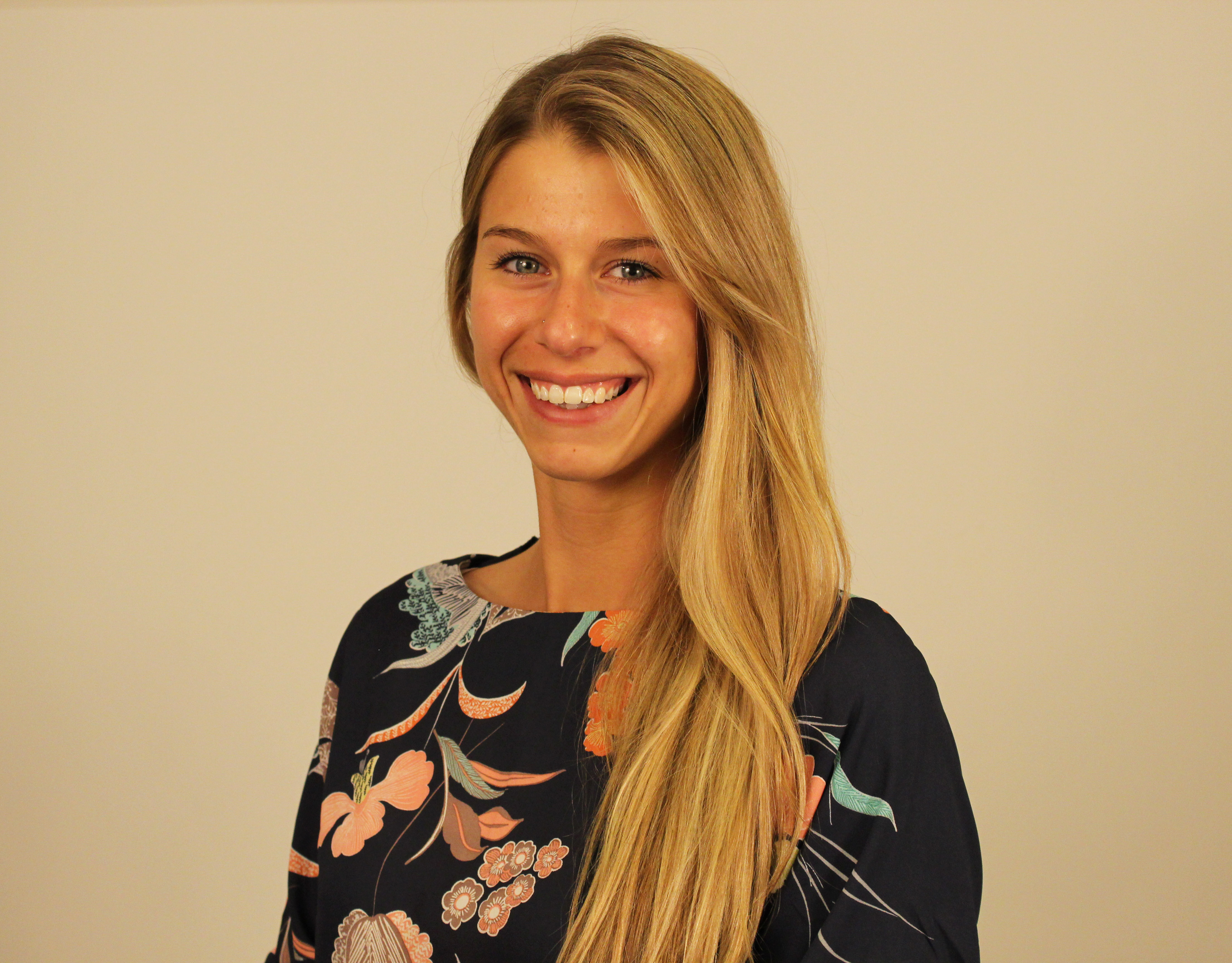 Young woman smiling wearing a black shirt with printed colors.